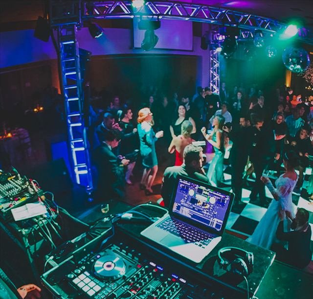 DJ comandando a pista em festa com iluminação colorida
